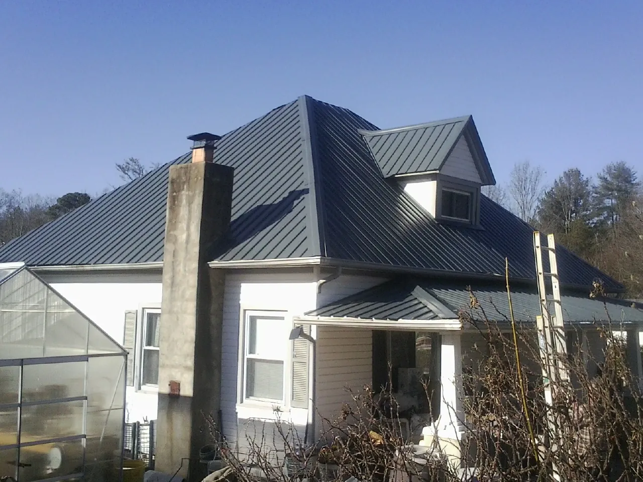 Dark blue standing seam metal roof on a white farmhouse with dormer — Slate & Tile Roof Repair by Roofing Brothers in Lake Ariel