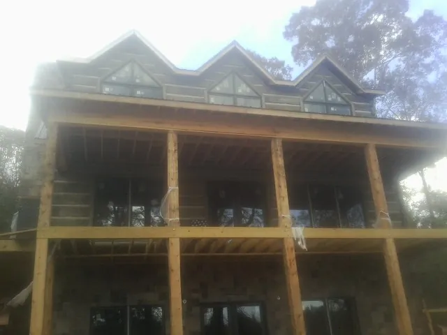Dormers and porch framing on a large log home under construction — Roof Coating work by our crew in Lake Ariel