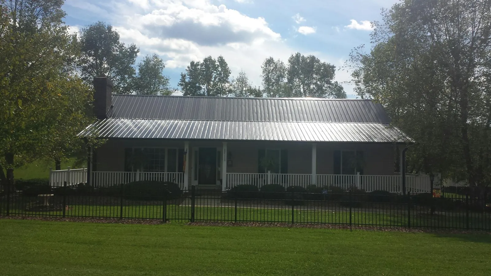 Gray metal roof on a brick ranch with a full width front porch — Gutter Guard Installation work by our crew in Lake Ariel