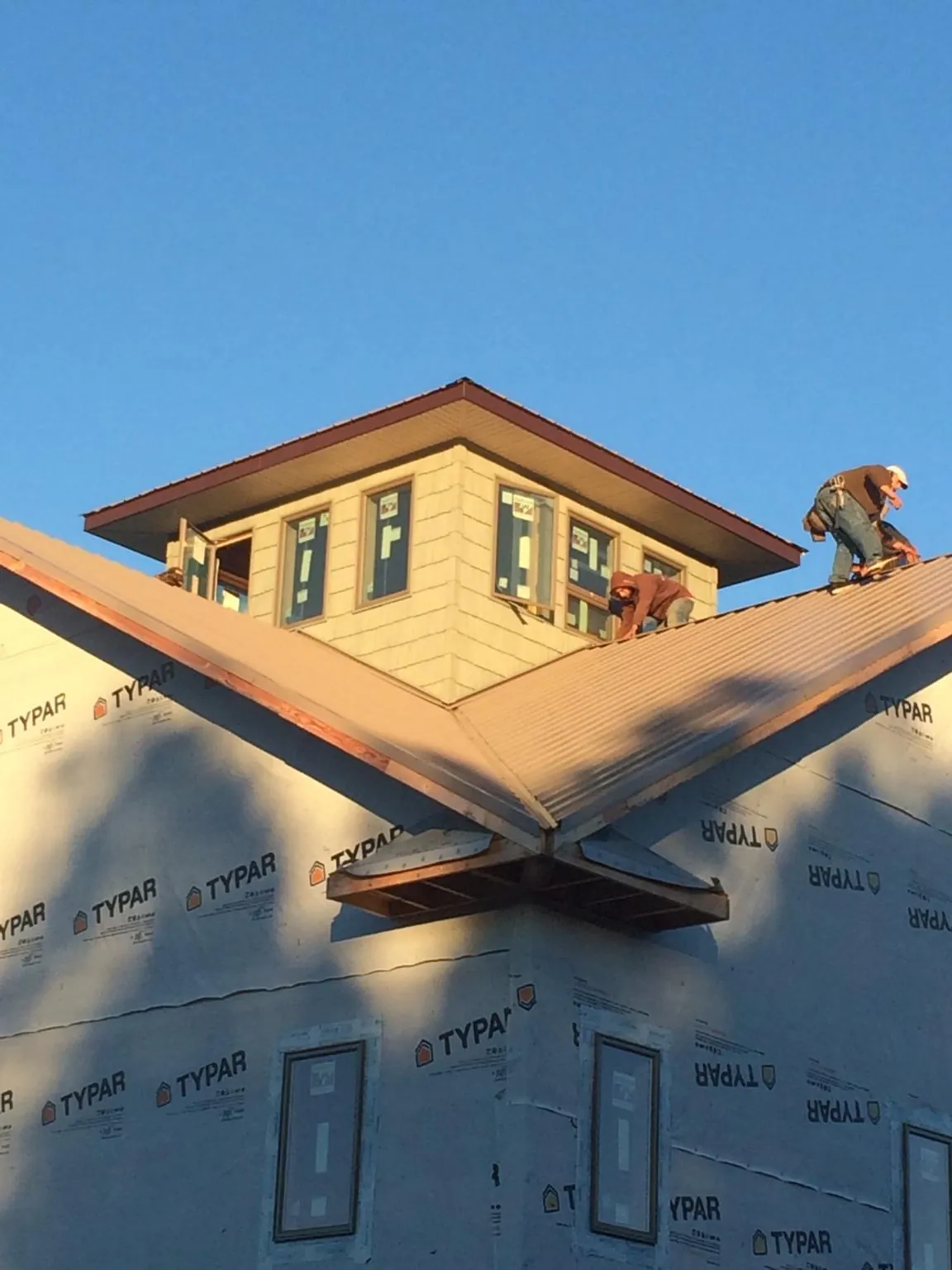 Roofers working around a rooftop cupola on a new metal roof at sunset — Roof Waterproofing in Lake Ariel by Roofing Brothers